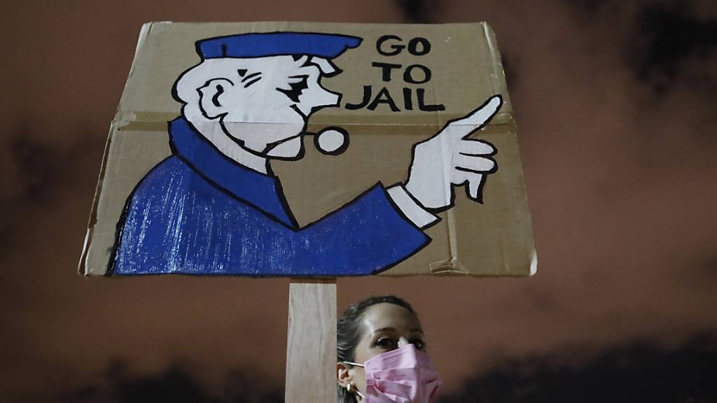 Eine Demonstrantin hält bei einem Protest in Tel Aviv ein Plakat in die Höhe. Foto: Ariel Schalit/AP/dpa