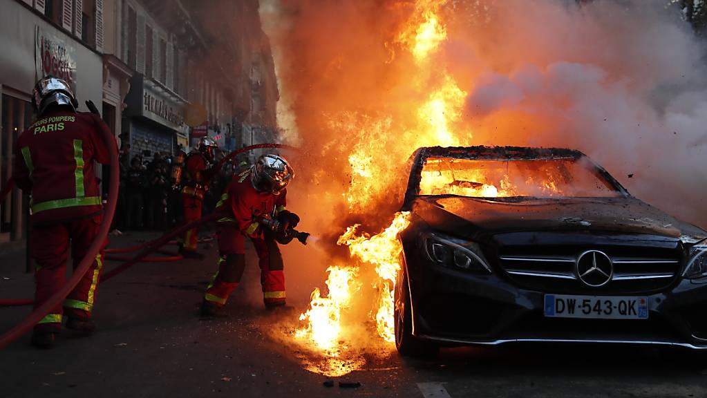 Die Feuerwehr löscht ein brennendes Auto in Paris. Foto: Francois Mori/AP/dpa