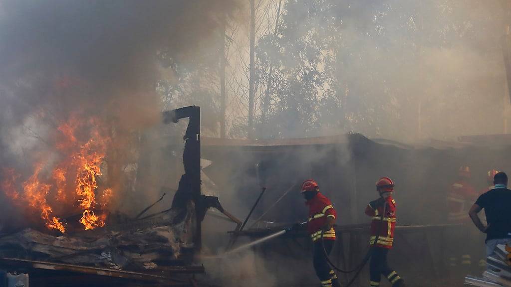 Feuerwehrleute sind während eines Brandes in einem Lagerhaus im Einsatz. Die Stadt im Norden des Landes ist von Waldbränden umgeben. Foto: Bruno Fonseca/AP