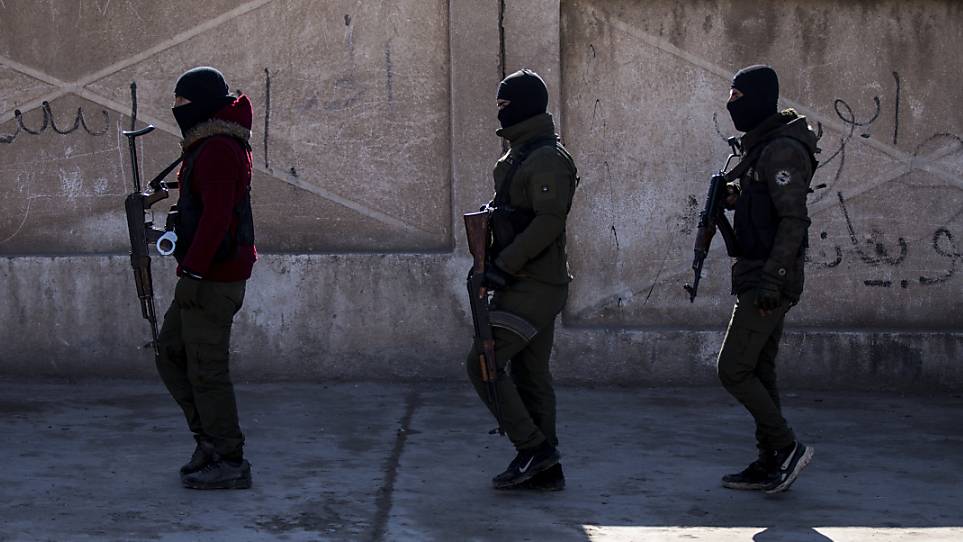 Von den USA unterstützte Soldaten der Demokratischen Kräfte Syriens gehen mit Waffen eine Straße entlang. Foto: Baderkhan Ahmad/AP/dpa