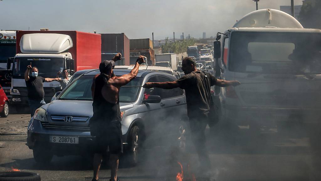 Demonstranten verhindern die Durchfahrt von Autos indem sie eine Hauptstraße mit brennenden Reifen blockieren. Die Demonstranten protestieren gegen die kollabierende Wirtschaft und den Lebensstandard im Libanon. Foto: Marwan Naamani/dpa