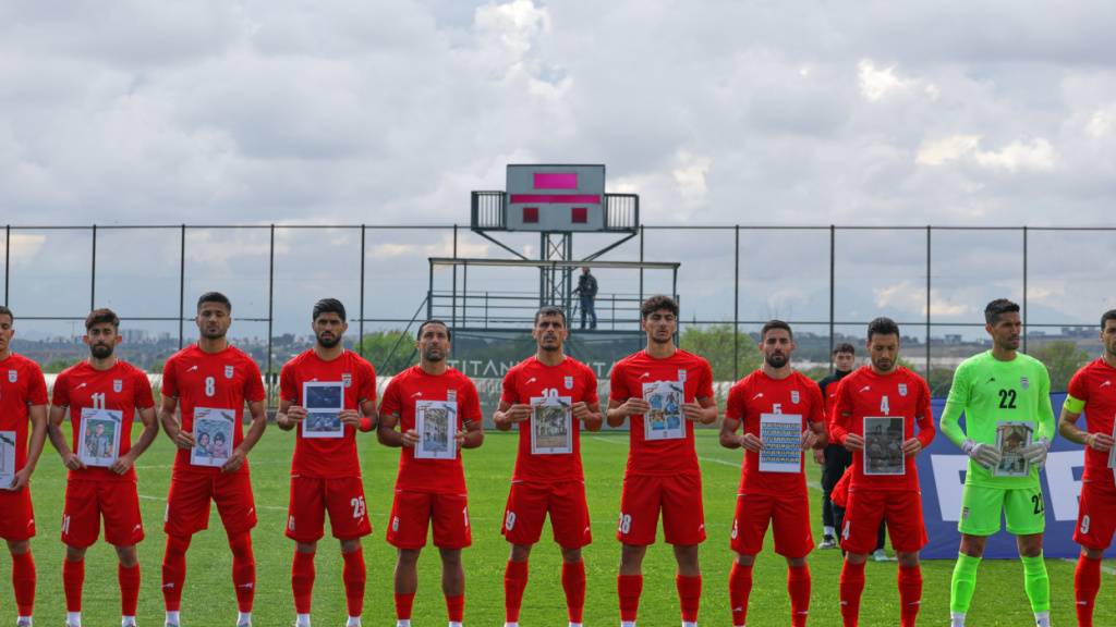 Die iranischen Spieler mit Bildern von Kindern, die gemäss Informationen der iranischen Delegation im Krieg getötet wurden