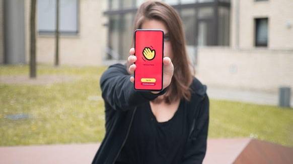 Auflösung zum Teaserbild: Eine junge Frau hält ein Smartphone mit der Houseparty-App, die es ermöglicht, in Gruppen virtuelle Videopartys zu feiern.