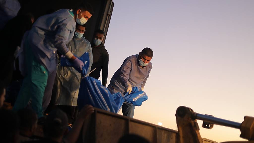 Sanitäter laden die Leichen von palästinensischen Opfern, die im Norden des Gazastreifens getötet wurden, in ein Massengrab. Foto: Mohammed Talatene/dpa