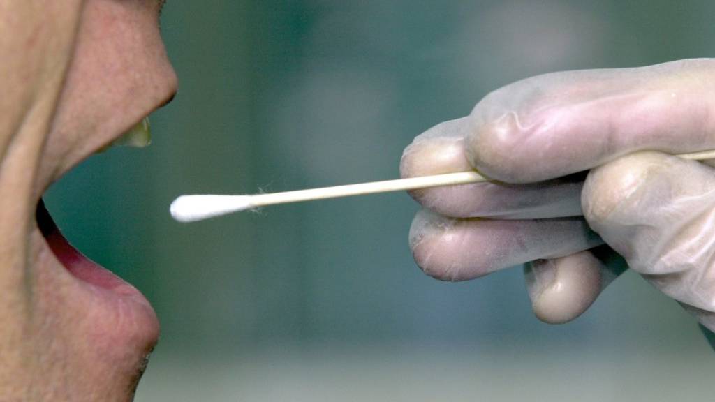 Einem Mann wird mit einem Wattestäbchen eine Speichelprobe zum DNA-Test entnommen. (Symbolbild)