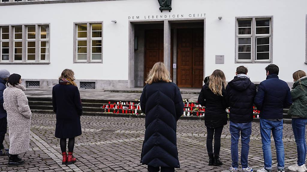 Menschen stehen zur Gedenkminute an für die bei einem Amoklauf an der Universität Heidelberg getötete Studentin vor dem Haupteingang der Neuen Universität. Foto: Uwe Anspach/dpa