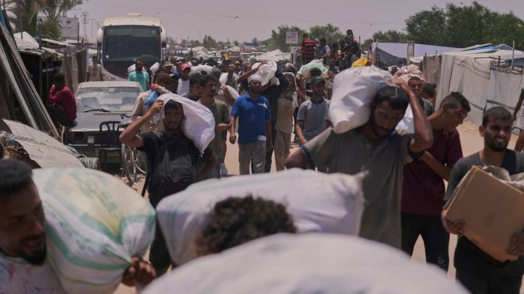dpatopbilder - Palästinenser tragen Taschen mit Lebensmitteln und humanitären Hilfspaketen, die von der Gaza Humanitarian Foundation geliefert wurden. Foto: Abdel Kareem Hana/AP/dpa