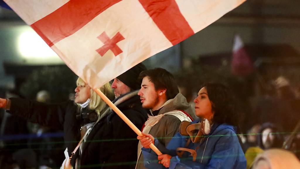 Eine Demonstrantin hält vor dem Parlamentsgebäude eine georgische Nationalflagge vor der Polizei. Foto: Zurab Tsertsvadze/AP/dpa