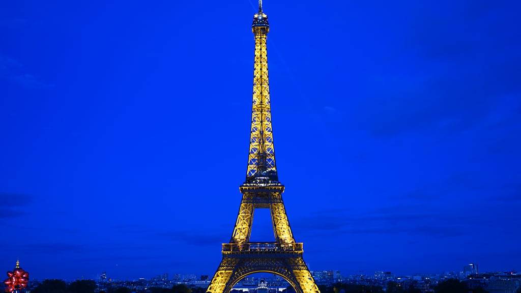 ARCHIV - Touristen stehen am Abend vor dem Eiffelturm. Kurz vor Beginn der Olympischen Spiele in Paris werden die Eintrittspreise für den Eiffelturm um rund 20 Prozent erhöht. Foto: Robert Michael/dpa