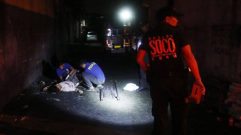 Philippinische Bundespolizisten untersuchen einen erschossenen Drogenhändler. Manila hat nun einer Untersuchung von Menschenrechtsverletzungen beim Anti-Drogen-Kampf zugestimmt. (Archiv)
