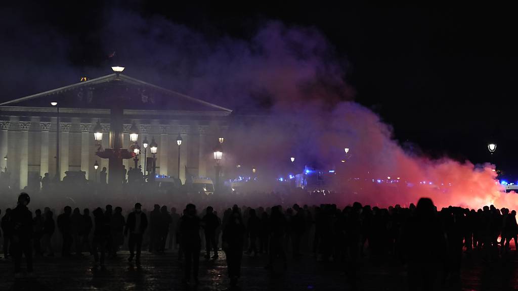 dpatopbilder - Menschen versammeln sich neben einer brennenden Barrikade vor der Nationalversammlung anlässlich eines Protestes gegen die Rentenreform. Foto: Lewis Joly/AP/dpa