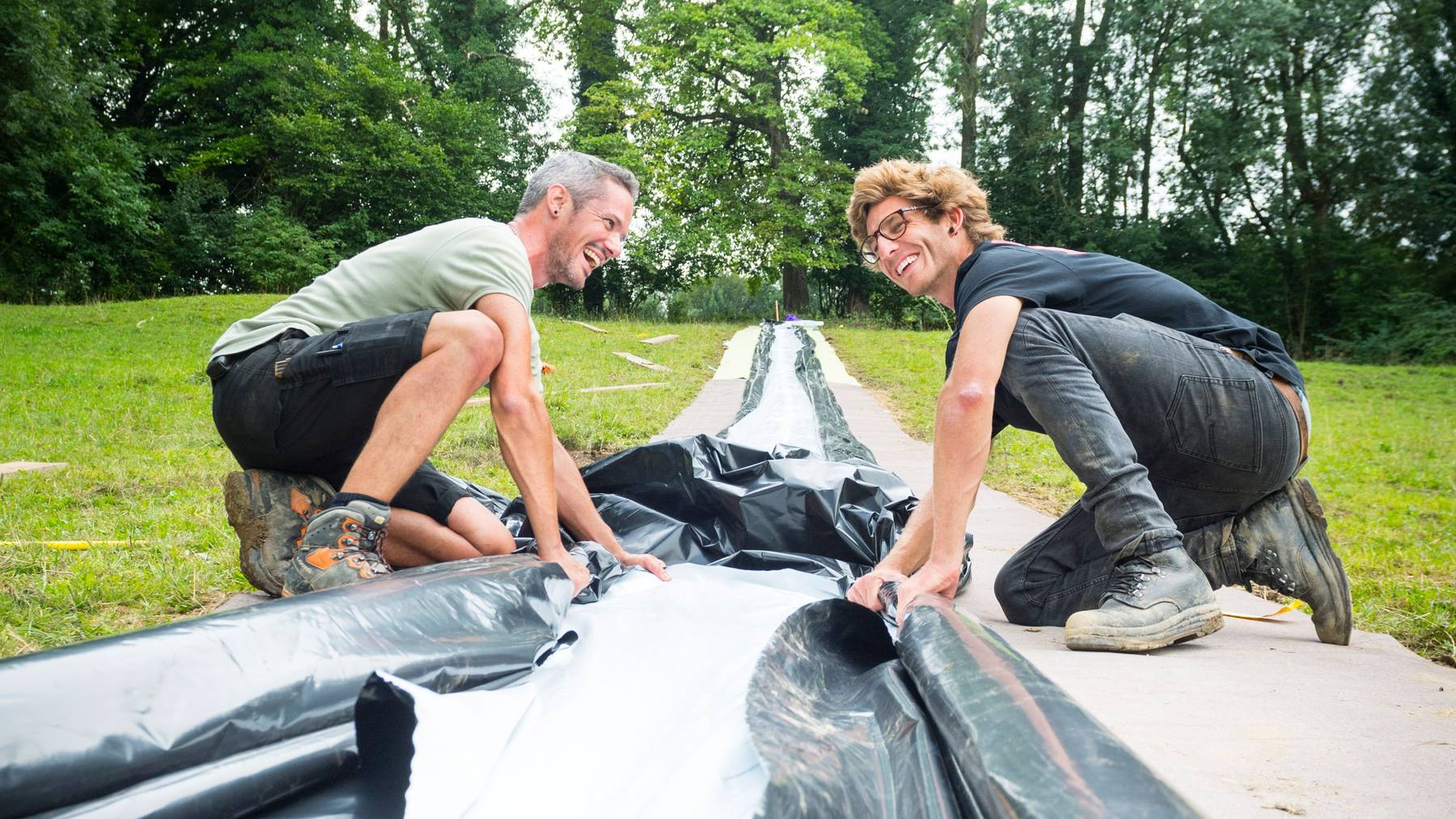 Die «Slip the shit»-Organisatoren Philipp Ammann (rechts) und Lukas Baumgartner bauen die Wasserrutsche auf.