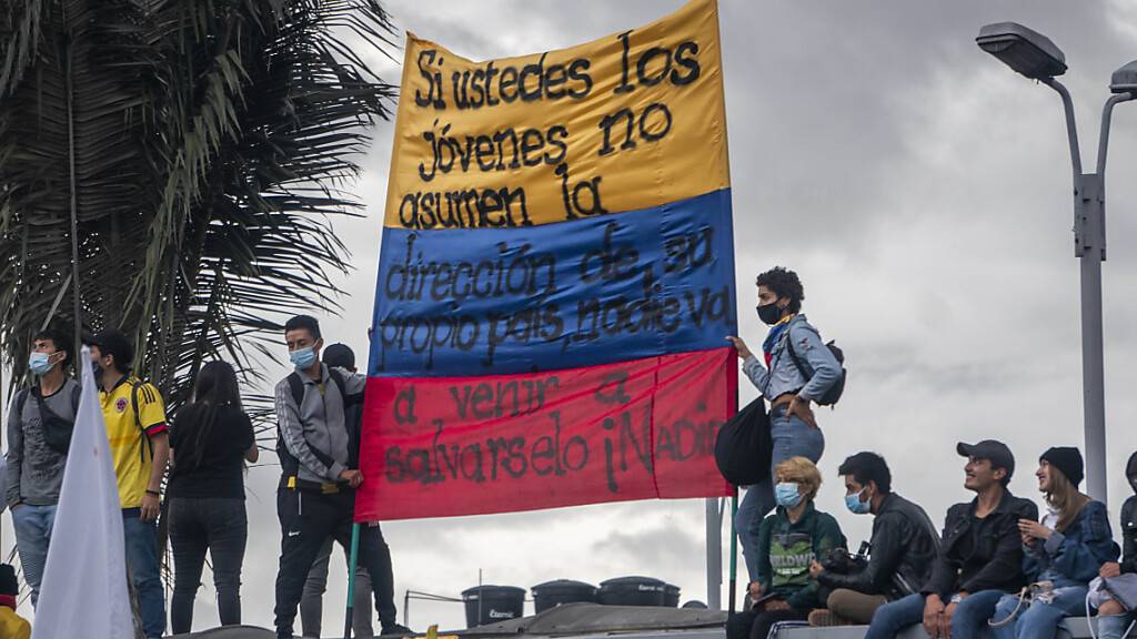 Menschen tragen eine kolumbianische Flagge, auf der geschrieben steht: «Wenn ihr jungen Leute nicht die Führung eures eigenen Landes übernehmt, wird niemand kommen, um euch zu retten, niemand». Foto: Daniel Garzon Herazo/ZUMA Wire/dpa
