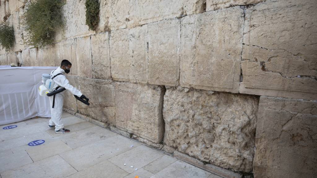 dpatopbilder - Ein Arbeiter verteilt Desinfektionsmittel als Vorsichtsmaßnahme gegen das Coronavirus an der Klagemauer, der heiligsten Stätte, an der Juden in Jerusalem beten können. Foto: Sebastian Scheiner/AP/dpa