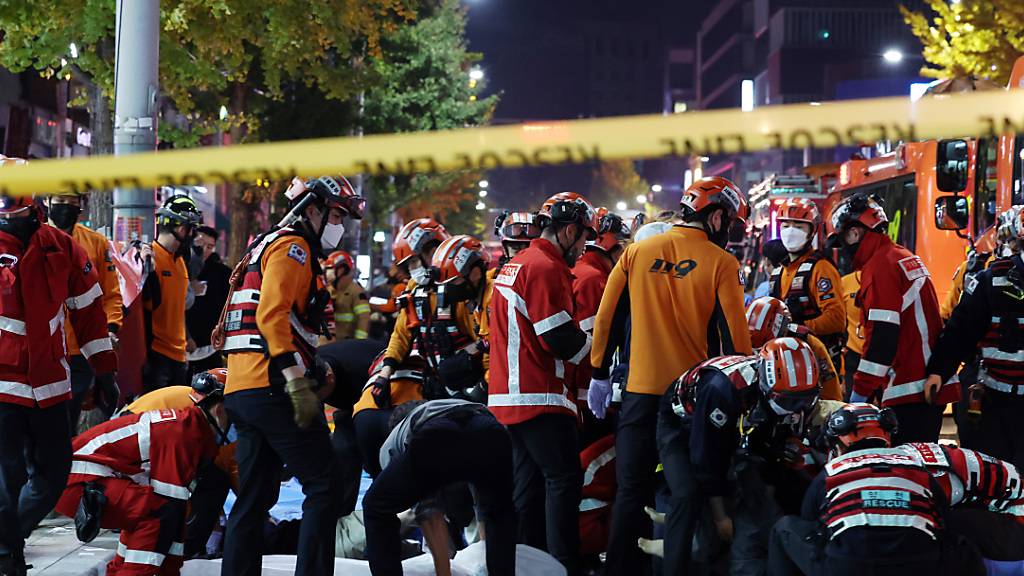 dpatopbilder - Rettungskräfte und Feuerwehrleute sind an der Unfallstelle im Einsatz. Dutzende Personen haben beim Ansturm auf Halloween-Feierlichkeiten in Seoul einen Herzstillstand erlitten. Foto: Lee Ji-Eun/Yonhap/AP/dpa