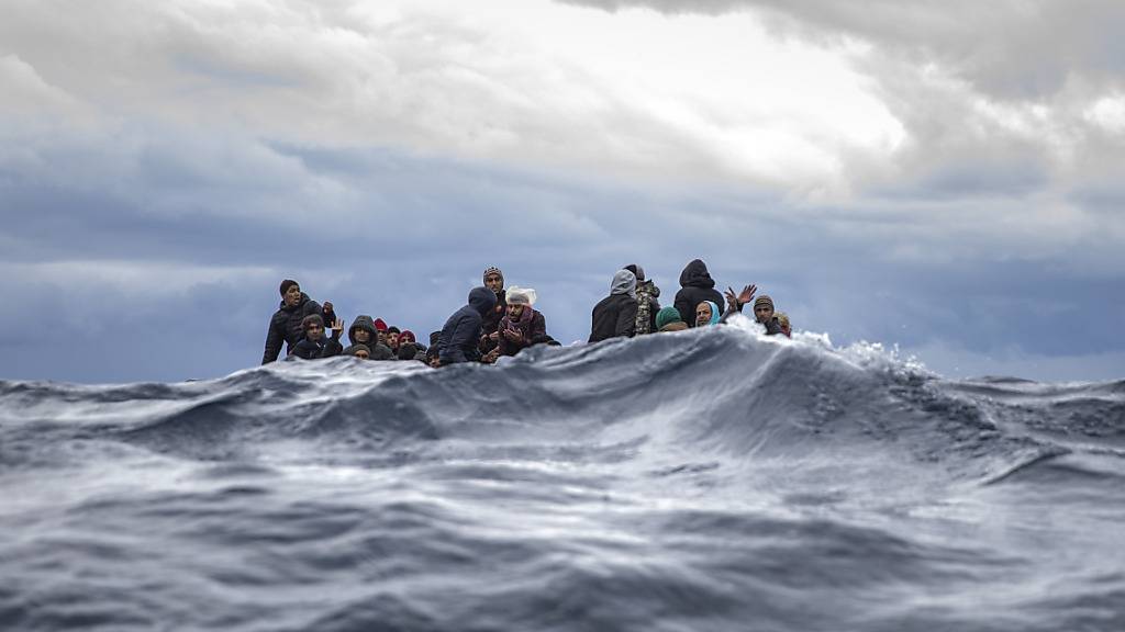 ARCHIV - Männer sitzen in einem überfüllten Holzboot im Mittelmeer vor der Küste von Libyen (Archivbild). Foto: Santi Palacios/AP/dpa