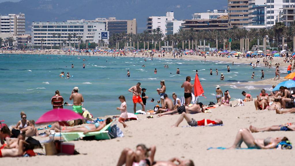 Menschen sonnen sich tagsüber am Strand von Arenal auf Mallorca. Nach einem Urteil des Obersten Gerichtshofs in Spanien sind die noch Corona-Beschränkungen bezüglich der Versammlungsfreiheit und auch die nächtliche Ausgangssperre nicht zulässig. Foto: Clara Margais/dpa