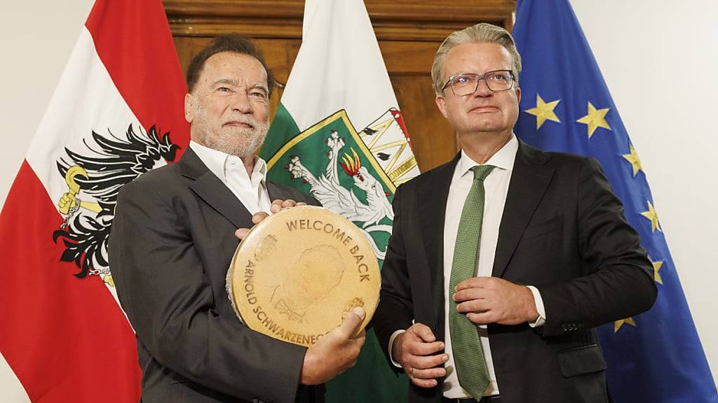 Arnold Schwarzenegger (l) bekommt einen Käse vom Landeshauptmann der Steiermark, Christopher Drexler (ÖVP) anlässlich der Präsentation einer Büste von Alt-Landeshauptmann Josef Krainer. Foto: Erwin Scheriau/APA/dpa