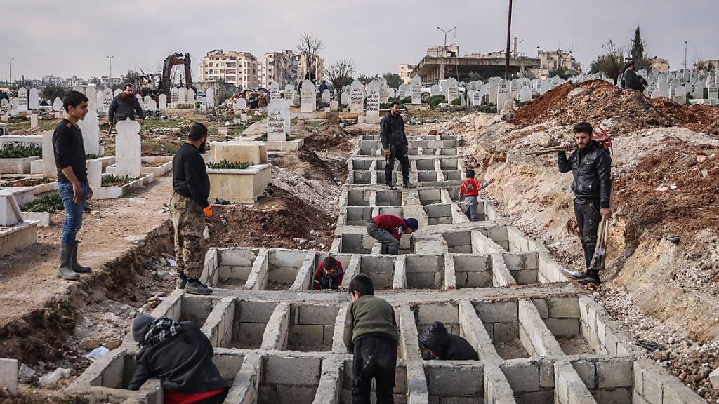 ARCHIV - Syrer heben entlang der türkisch-syrischen Grenze Mitte Februar Gräber für ihre Angehörigen aus, die bei dem verheerenden Erdbeben ums Leben gekommen sind. Foto: Anas Alkharboutli/dpa/Archiv