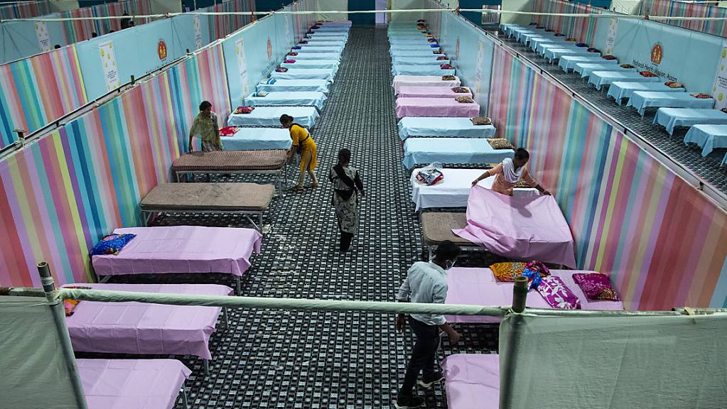 dpatopbilder - Arbeiter stellen provisorische Betten für Corona-Patienten in einer Stadionhalle auf. Foto: Anupam Nath/AP/dpa