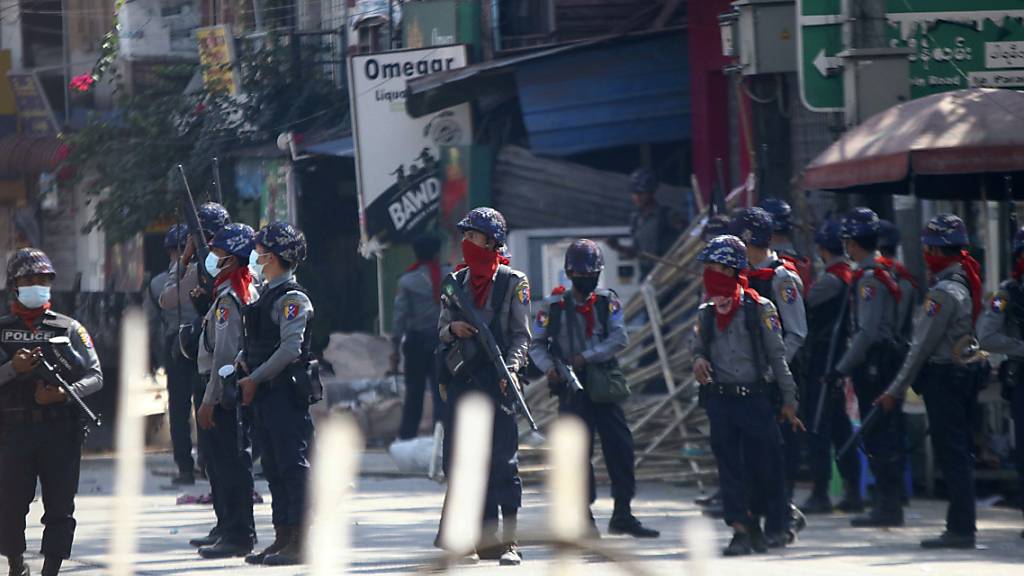 Bewaffnete Polizisten stehen auf einer Straße, um eine Demonstration gegen den Militärputsch zu verhindern. Foto: Str/AP/dpa
