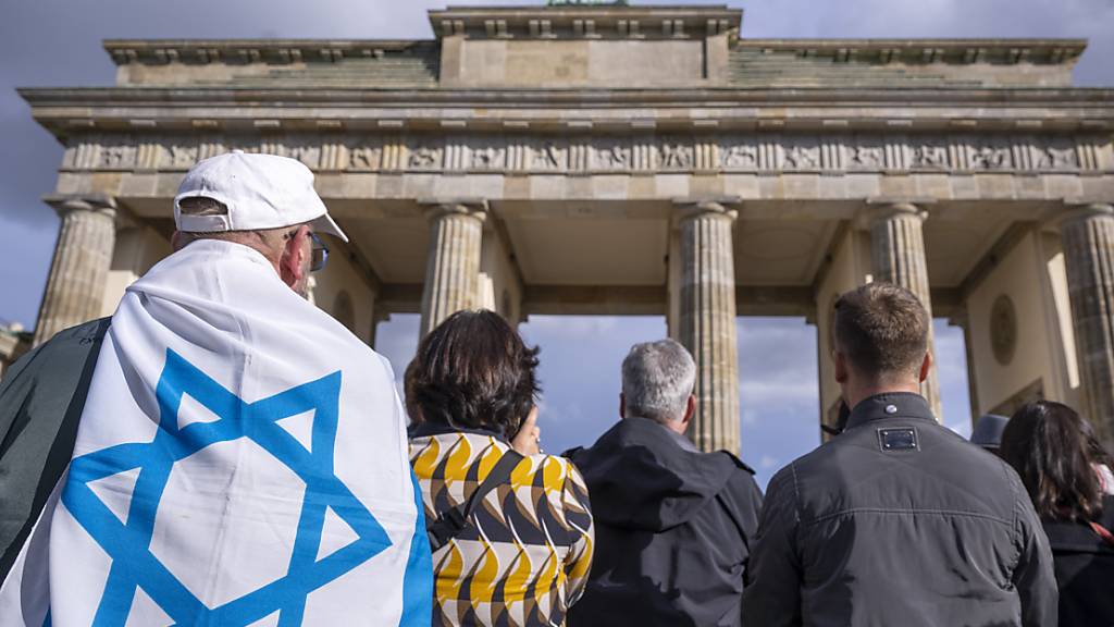 Ein Mann mit der Flagge von Israel auf seinem Rücken nimmt an der Kundgebung «Aufstehen gegen Terror, Hass und Antisemitismus - in Solidarität und Mitgefühl mit Israel» vor dem Brandenburger Tor teil. Foto: Monika Skolimowska/dpa