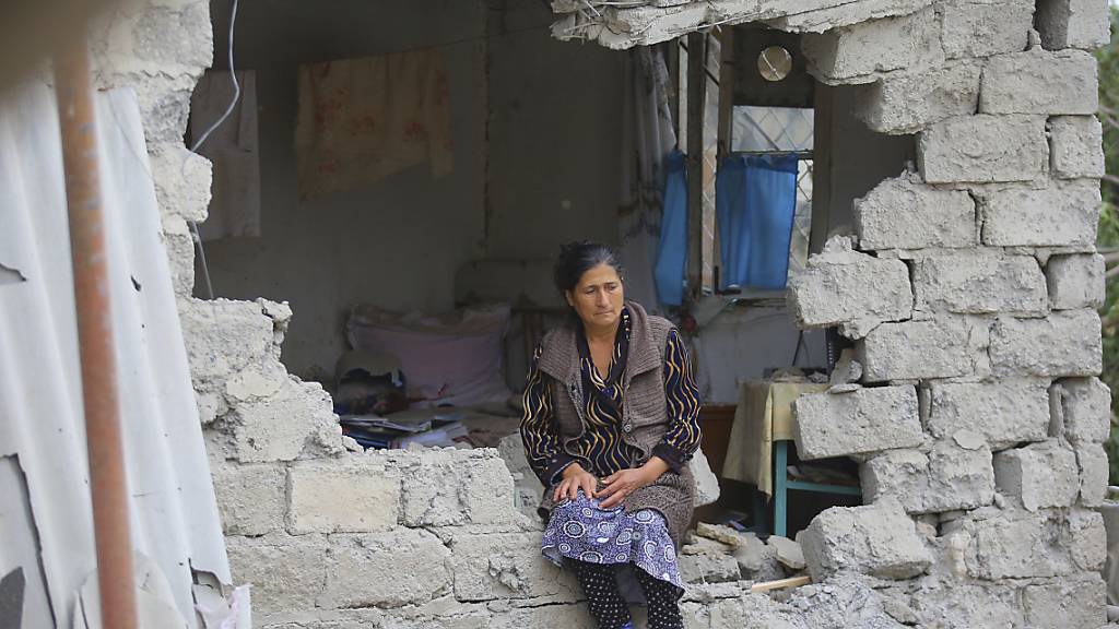 Eine Frau sitzt nach einem Beschuss der armenischen Artillerie inmitten der Trümmer ihres Hauses. Russland hat nach neuen Kämpfen die beiden verfeindeten Nachbarn Armenien und Aserbaidschan an die strikte Einhaltung der ausgehandelten Waffenruhe für die Unruheregion Berg-Karabach erinnert. Foto: Aziz Karimov/AP/dpa
