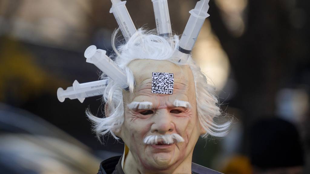 Eine Person trägt eine Latexmaske, an der Spritzen befestigt sind. In Bukarest wird gegen Impfungen, die Einführung des «Grünen Passes» und Einschränkungen in Bezug auf das Coronavirus demonstriert.