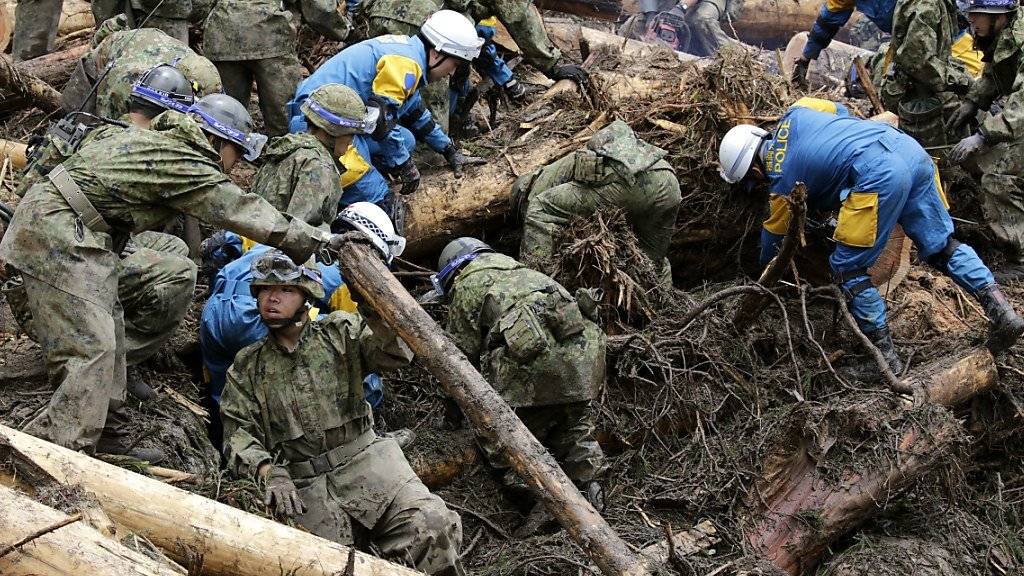 Im Dorf Toho (Präfektur Fukuoka) suchen Rettungskräfte und Soldaten unter Schlamm, Geröll, Geäst und Baumstämmen nach Vermissten.