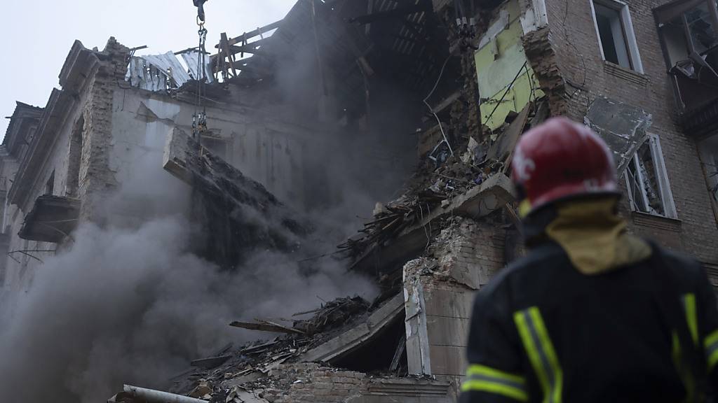 ARCHIV - Feuerwehrleute des staatlichen ukrainischen Katastrophenschutzes beseitigen die Trümmer des Gebäudes, das durch einen Angriff zerstört wurde. Foto: Evgeniy Maloletka/AP/dpa