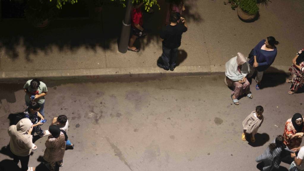 Menschen in Rabatsuchen nach einem Erdbeben Schutz und überprüfen ihre Mobiltelefone auf Neuigkeiten. Foto: Mosa'ab Elshamy/AP