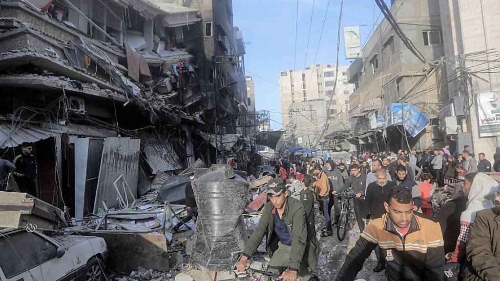 Palästinenser stehen vor den stark beschädigten Gebäuden in Chan Junis nach einem israelischen Angriff. Foto: Mohammed Talatene/dpa