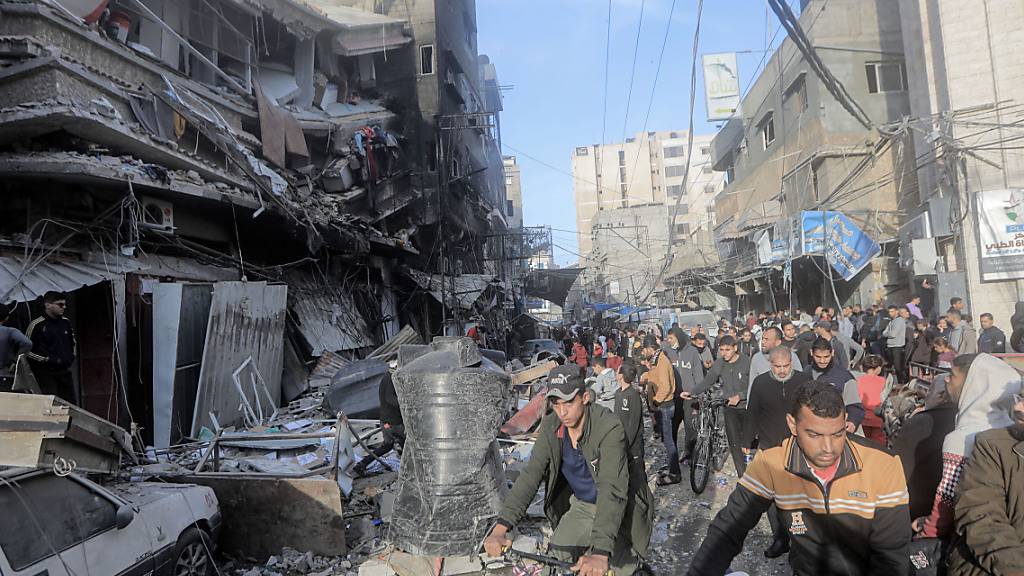 Palästinenser stehen vor den stark beschädigten Gebäuden in Chan Junis nach einem israelischen Angriff. Foto: Mohammed Talatene/dpa