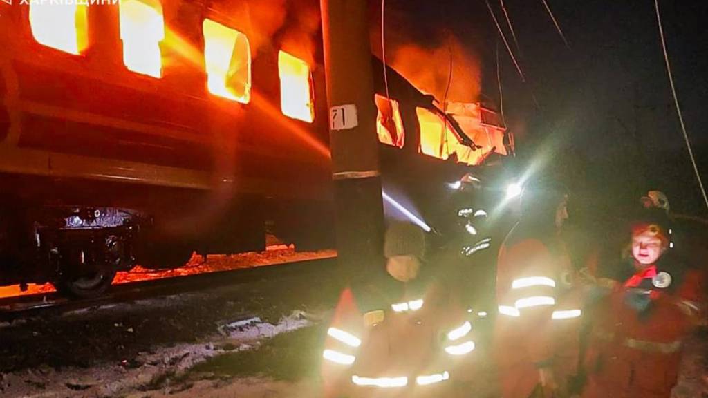 HANDOUT - Auf diesem vom ukrainischen Katastrophenschutz zur Verfügung gestellten Foto bekämpfen Feuerwehrleute das Feuer, nachdem russische Drohnen einen Personenzug in der Region Charkiw (Ukraine) getroffen und in Brand gesetzt haben. Foto: -/Ukrainian Emergency Service/dpa - ACHTUNG: Nur zur redaktionellen Verwendung und nur mit vollständiger Nennung des vorstehenden Credits