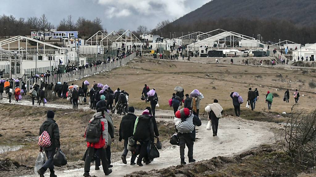 Migranten gehen am 30. Dezember 2020 mit ihren Habseligkeiten zurück zum Lager Lipa. Foto: Kemal Softic/AP/dpa