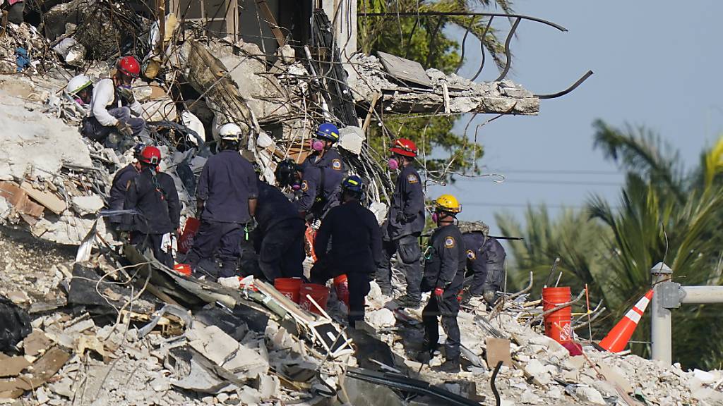 Rettungskräfte durchsuchen die Trümmer des Champlain Towers. Nach dem Teileinsturz eines zwölfstöckigen Wohnhauses im US-Bundesstaat Florida sind in den Trümmern weitere Todesopfer gefunden worden. Foto: Lynne Sladky/AP/dpa