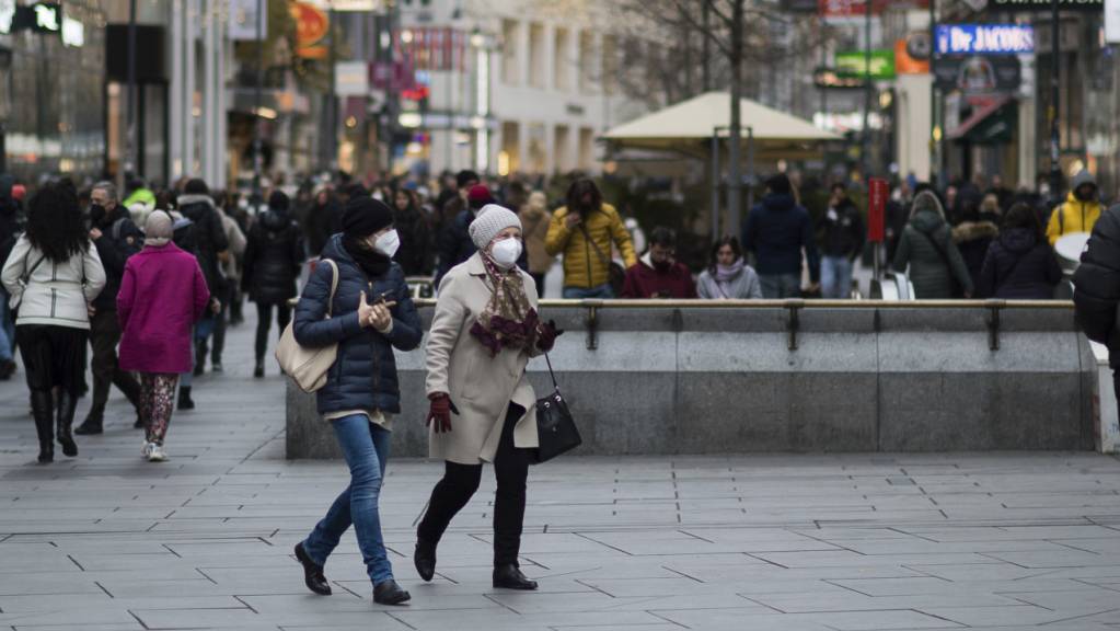 Zwei Personen mit Mund-Nasen-Schutz gehen über eine Einkaufsstraße. Seit November gelten in Österreich Coronabeschränkungen für ungeimpfte Bürgerinnen und Bürger.