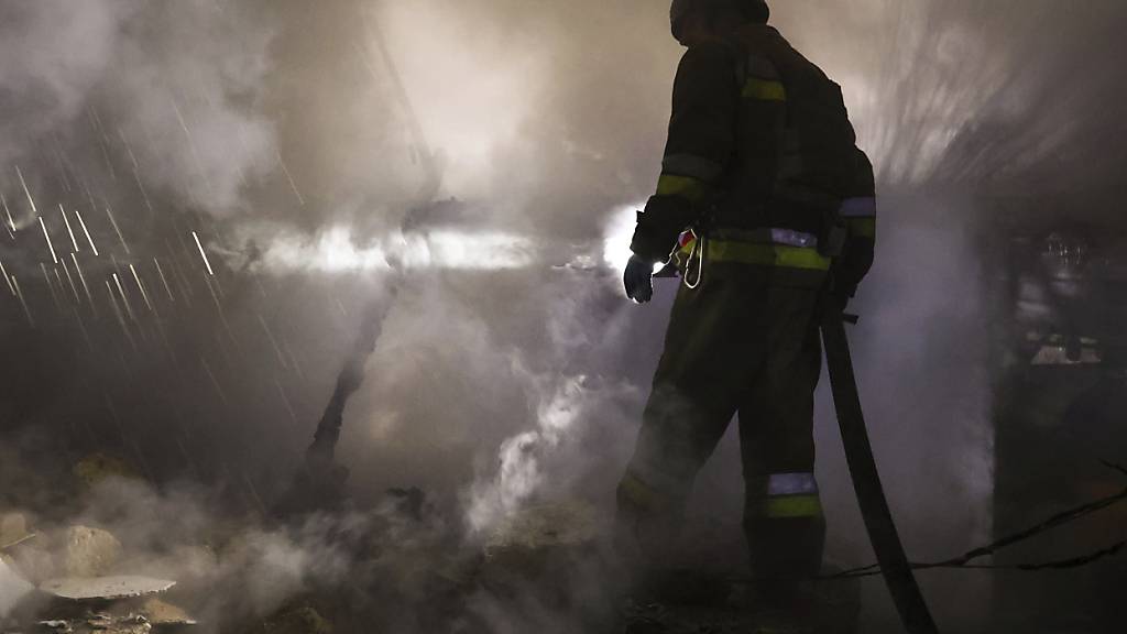 HANDOUT - Auf diesem vom ukrainischen Katastrophenschutz zur Verfügung gestellten Bild arbeitet ein Feuerwehrmann an der Stelle eines russischen Angriffs auf ein Wohngebiet. Foto: Ukrainischer Katastrophenschutz/AP/dpa - ACHTUNG: Nur zur redaktionellen Verwendung und nur mit vollständiger Nennung des vorstehenden Credits