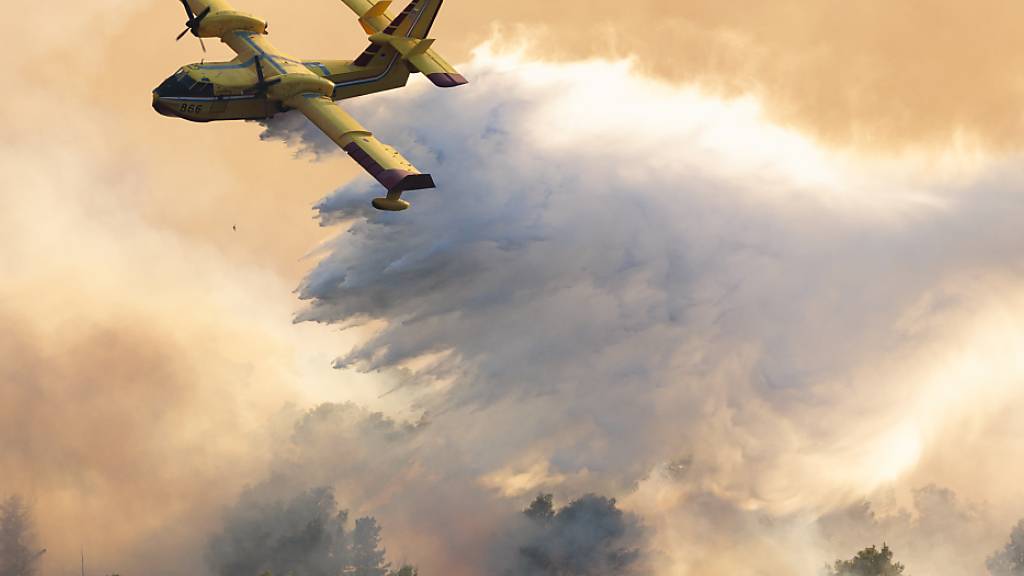 ARCHIV - Ein Löschflugzeug versprüht Wasser, um einen Waldbrand auf der Insel Ciovo zu löschen. Foto: Miroslav Lelas/AP/dpa