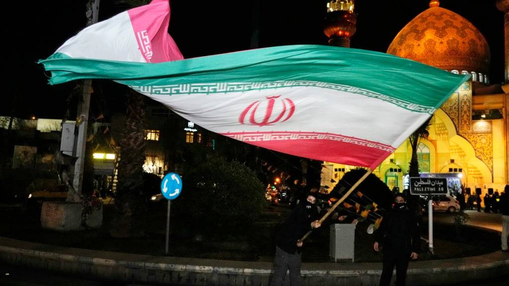 ARCHIV - Ein Demonstrant schwenkt eine iranische Flagge bei einer Feier anlässlich der Ankündigung einer Waffenruhe zwischen der Hamas und Israel. Foto: Vahid Salemi/AP/dpa