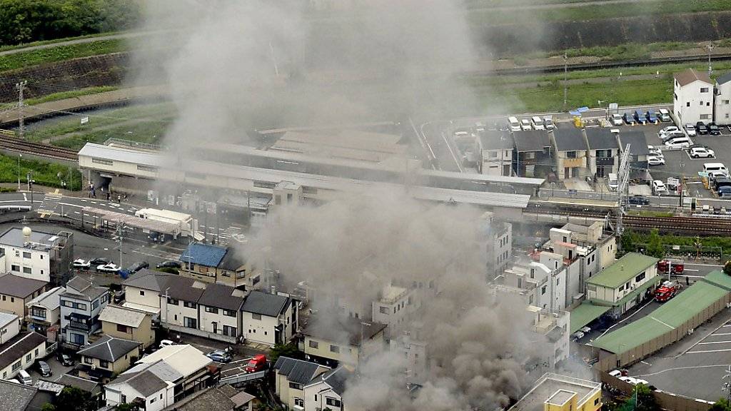 Nach dem verheerenden Brandanschlag auf ein Filmstudio in Kyoto steigt eine Rauchsäule über dem Gebäude auf.