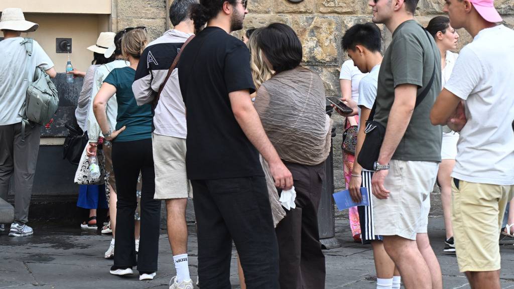 Eine Schlange hat sich vor einem Trinkwasser-Brunnen gebildet. Touristen besuchen die Stadt trotz der hohen Temperaturen. Foto: Aleandro Biagianti / Agf/AGF via ZUMA Press/dpa