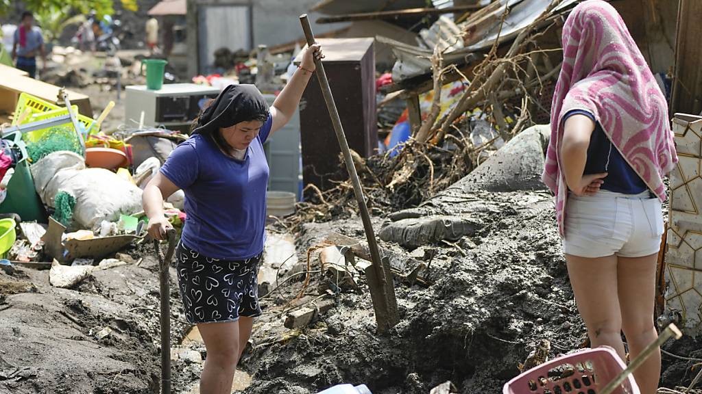 Menschen in der philippinischen Provinz Batangas versuchen Habseligkeiten aus ihren beim Tropenstrum Trami beschädigten Häusern zu bergen. Foto: Aaron Favila/AP/dpa