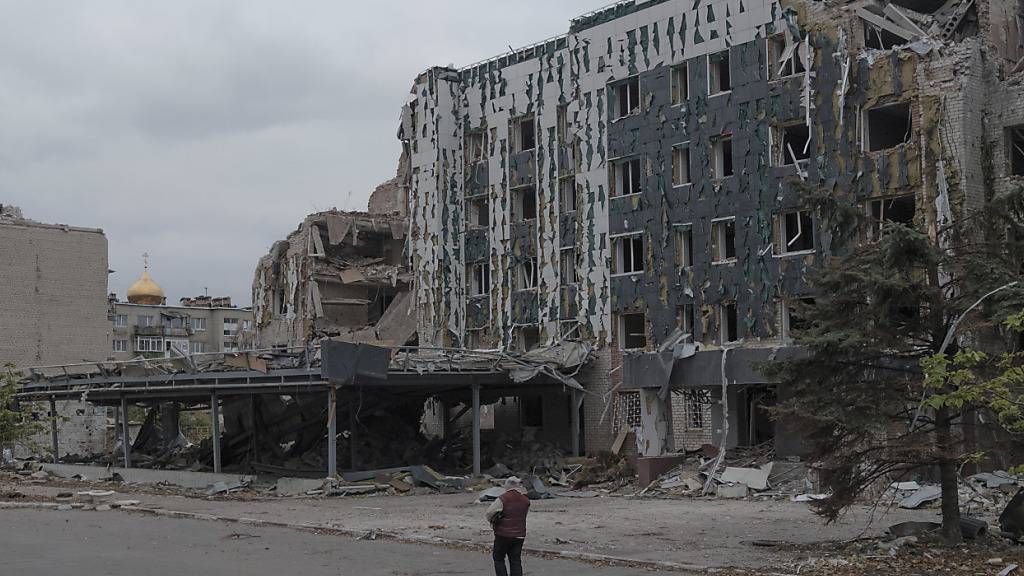 ARCHIV - Eine Frau läuft an dem von russischen Luftangriffen zerstörten Hotel Druschba in Pokrowsk entlang. Foto: George Ivanchenko/AP/dpa