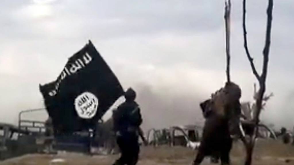 ARCHIV - IS-Kämpfer laufen mit einer IS-Flagge (Archivbild). Foto: Uncredited/Amaq News Agency/AP/dpa