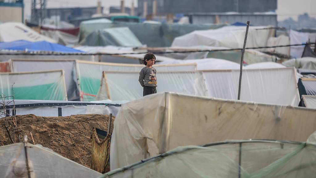 Ein Kind steht neben einem Zelt seiner Familie in einem Lager für Vertriebene. Foto: Mohammed Talatene/dpa