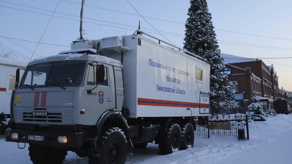 Ein Lastwagen des russischen Katastrophenschutzministeriums steht in der Listwjaschnaja-Mine (rechts) in der Nähe von Belowo in der Region Kemerowo im Südwesten Sibiriens, Russland. Foto: Sergei Gavrilenko/AP/dpa