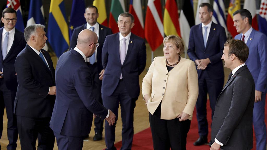 Angela Merkel (M) spricht mit Charles Michel (Mitte links), Präsident des Europäischen Rates, und Emmanuel Macron (rechts), Präsident von Frankreich. Beim Gipfel der EU-Staats- und Regierungschefs ist es zu keiner Einigung gekommen, wie langfristig gegen hohe Energiepreise vorgegangen werden soll. Foto: Olivier Matthys/AP/dpa