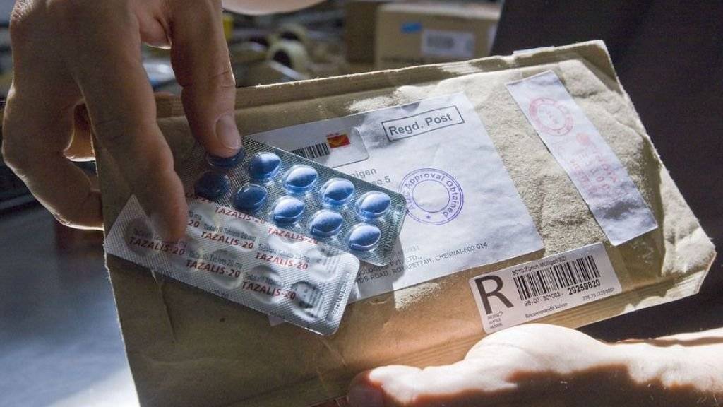 Ein Mitarbeiter des Postzollamtes in Zürich zeigt ein Päckchen mit Fälschungen des Potenzmittels «Viagra». (Archivbild)