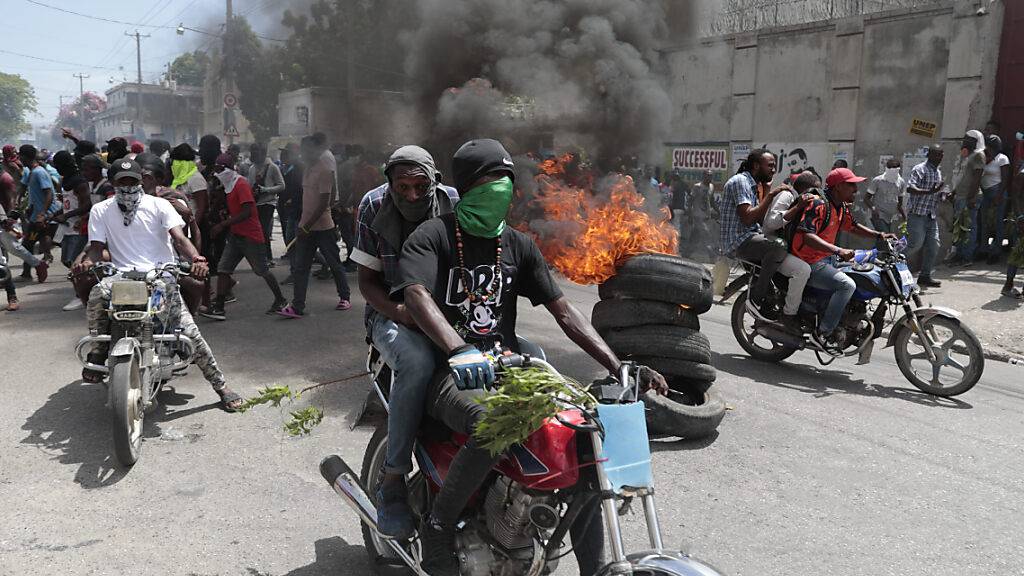 Demonstranten fahren mit ihren Motorrädern an einer brennenden Barrikade vorbei, während sie gegen die Unsicherheit in Port-au-Prince protestieren. Foto: Odelyn Joseph/AP
